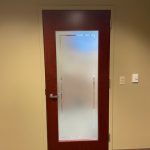 fasara film on a partially glass door and mahogany border with a decorative gap near the edge of the glass following the wood